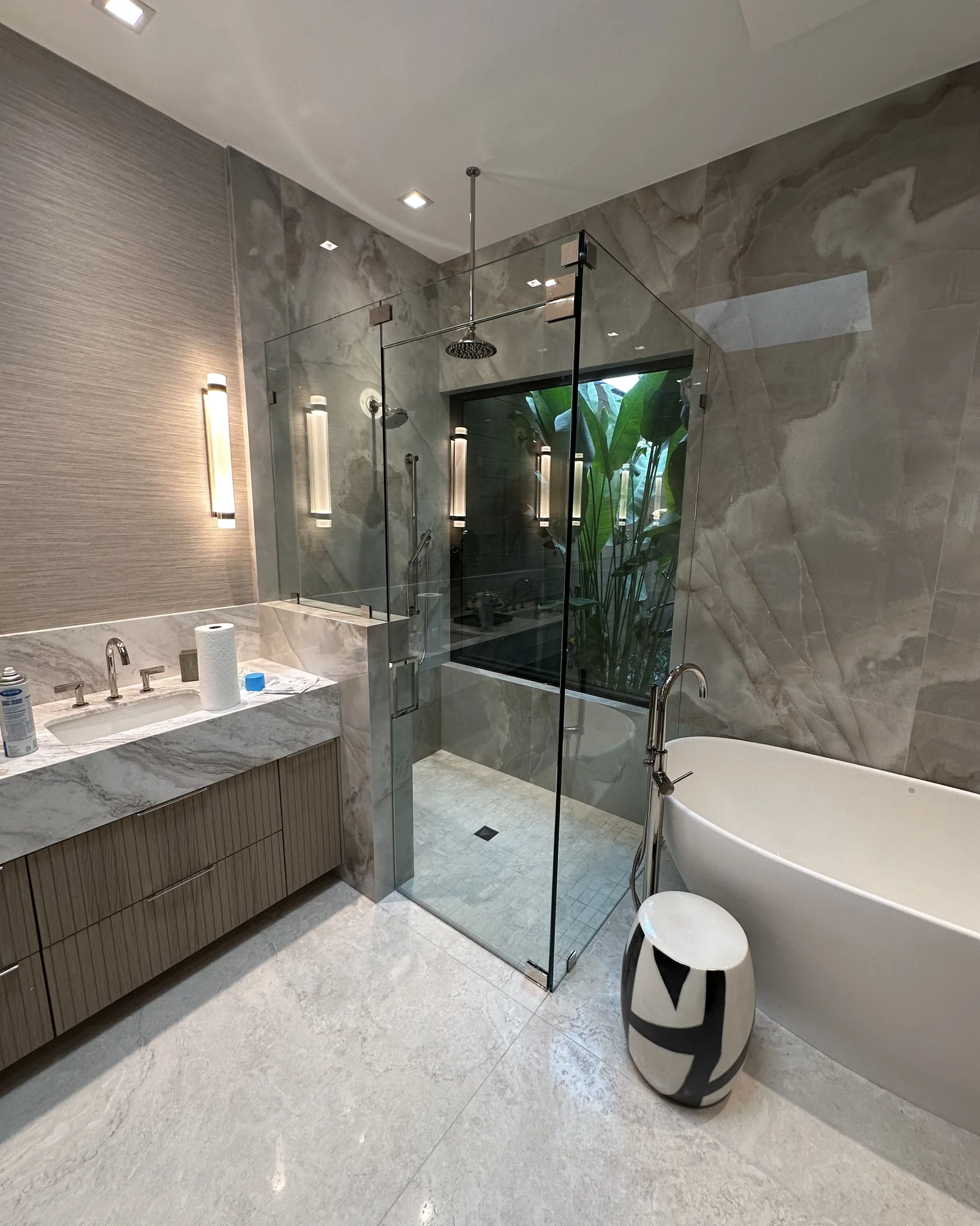 After: frameless glass walk-in shower in a bathroom with grey onyx walls