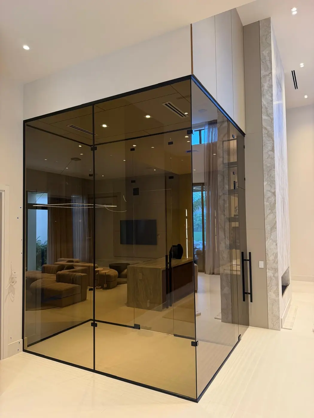 Bronze-tinted glass enclosure with a matte black frame in a bright living space