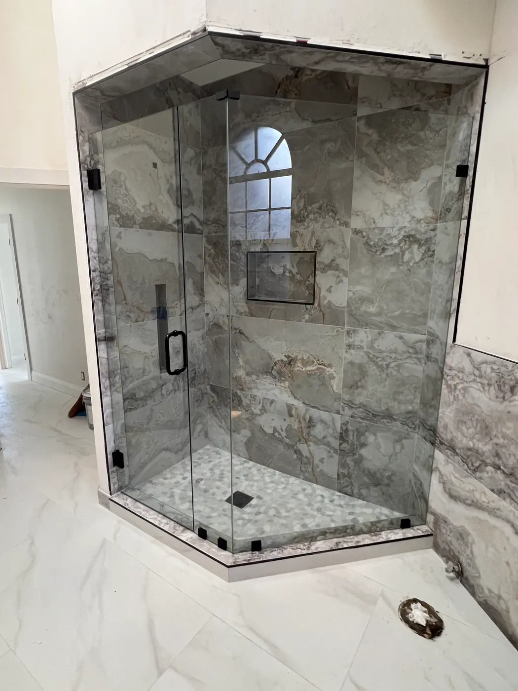 Neo-angle shower in grey stone tile with matte black hinges and handle