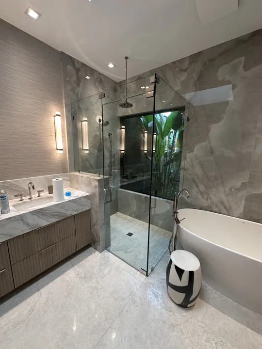 Walk-in shower with onyx walls beside a freestanding tub