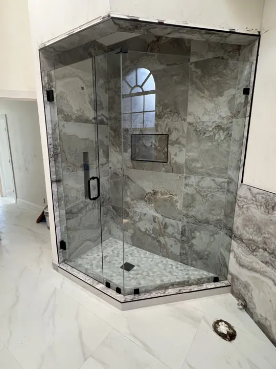 Neo-angle shower with black hardware and stone walls