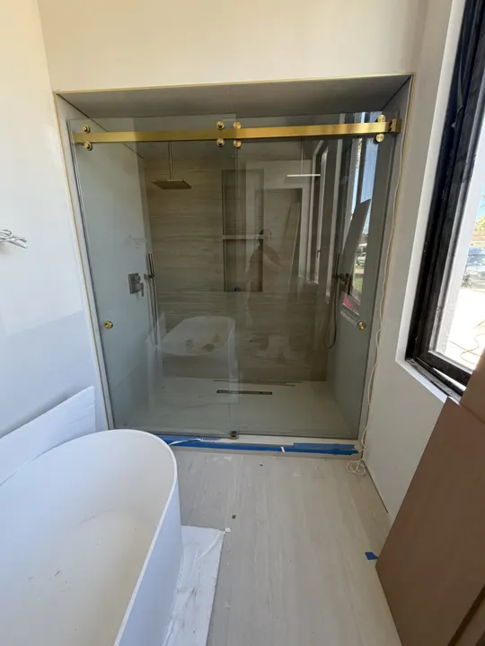 Sliding door on brass hardware beside a freestanding tub