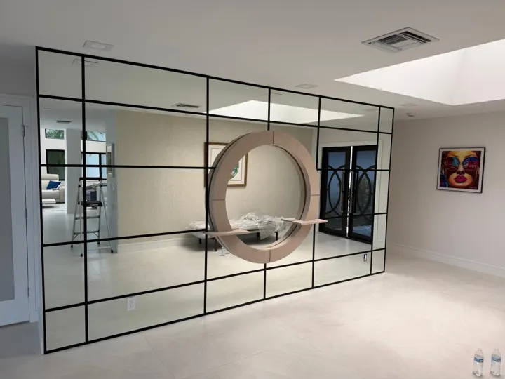 Mirror wall with black grid trim and a round accent