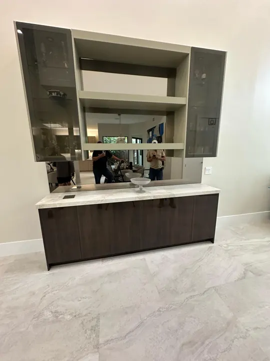 Mirror wall over a bar cabinet with smoked glass doors